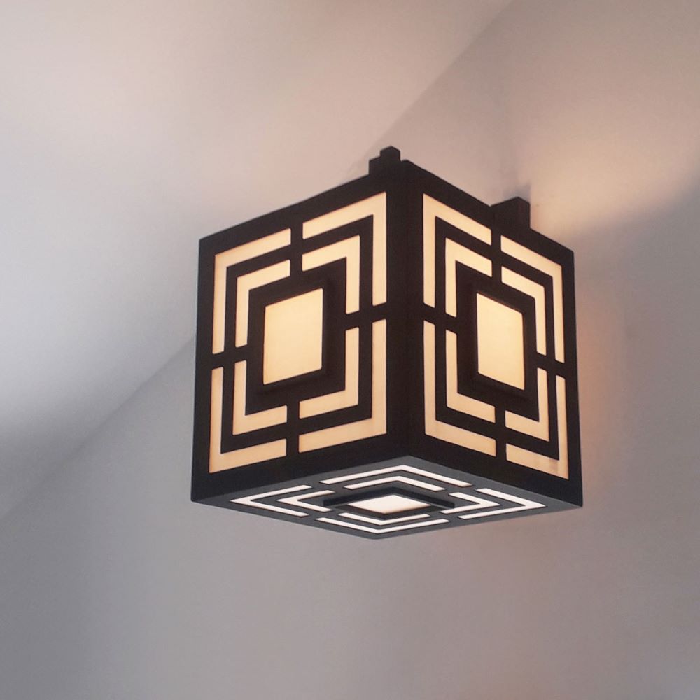 Black geometric wall sconce in steel with square design and filtered light. Cubic form with soft, even illumination.